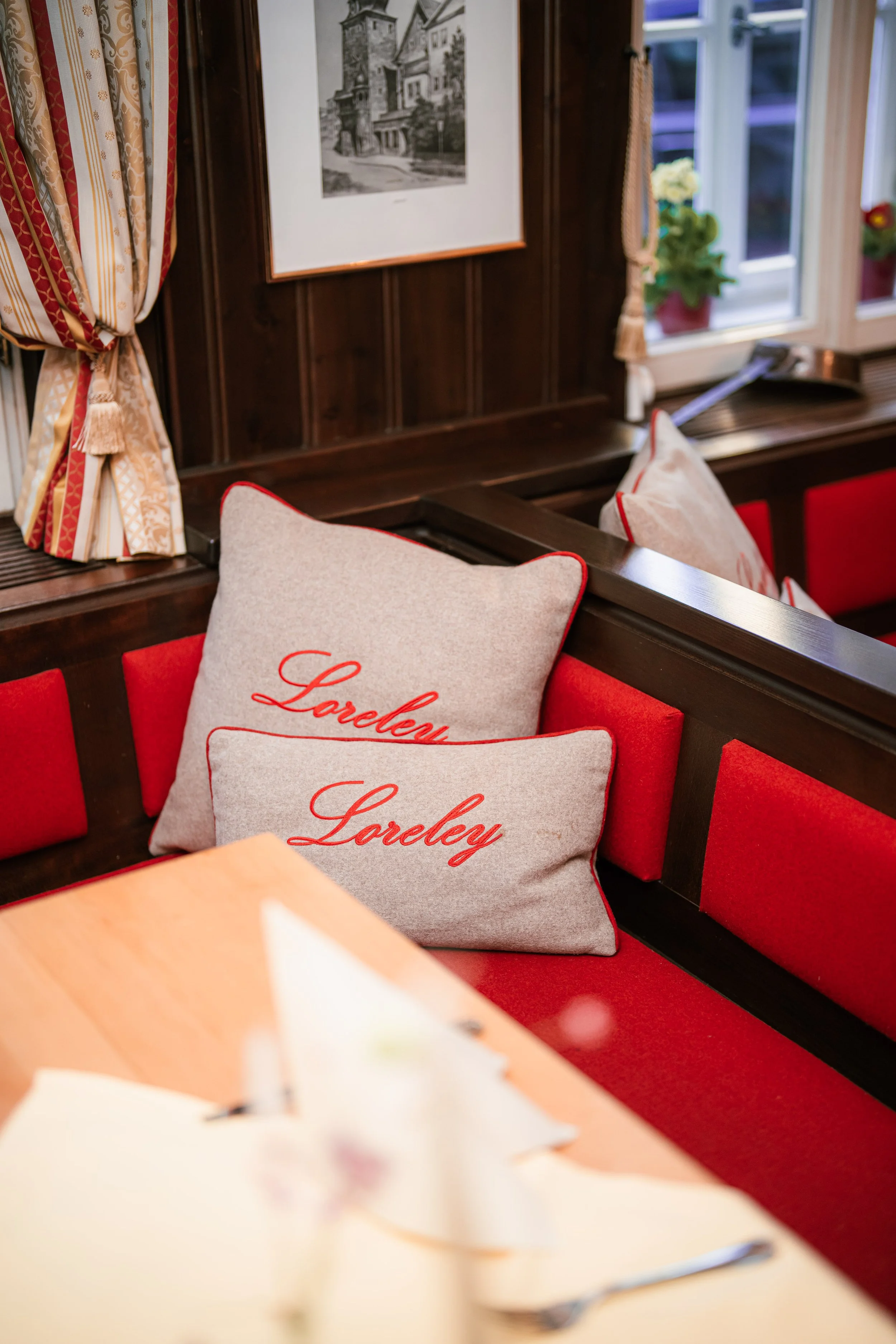 Sitzbank mit roten Polstern und Kissen mit „Loreley"-Stickerei